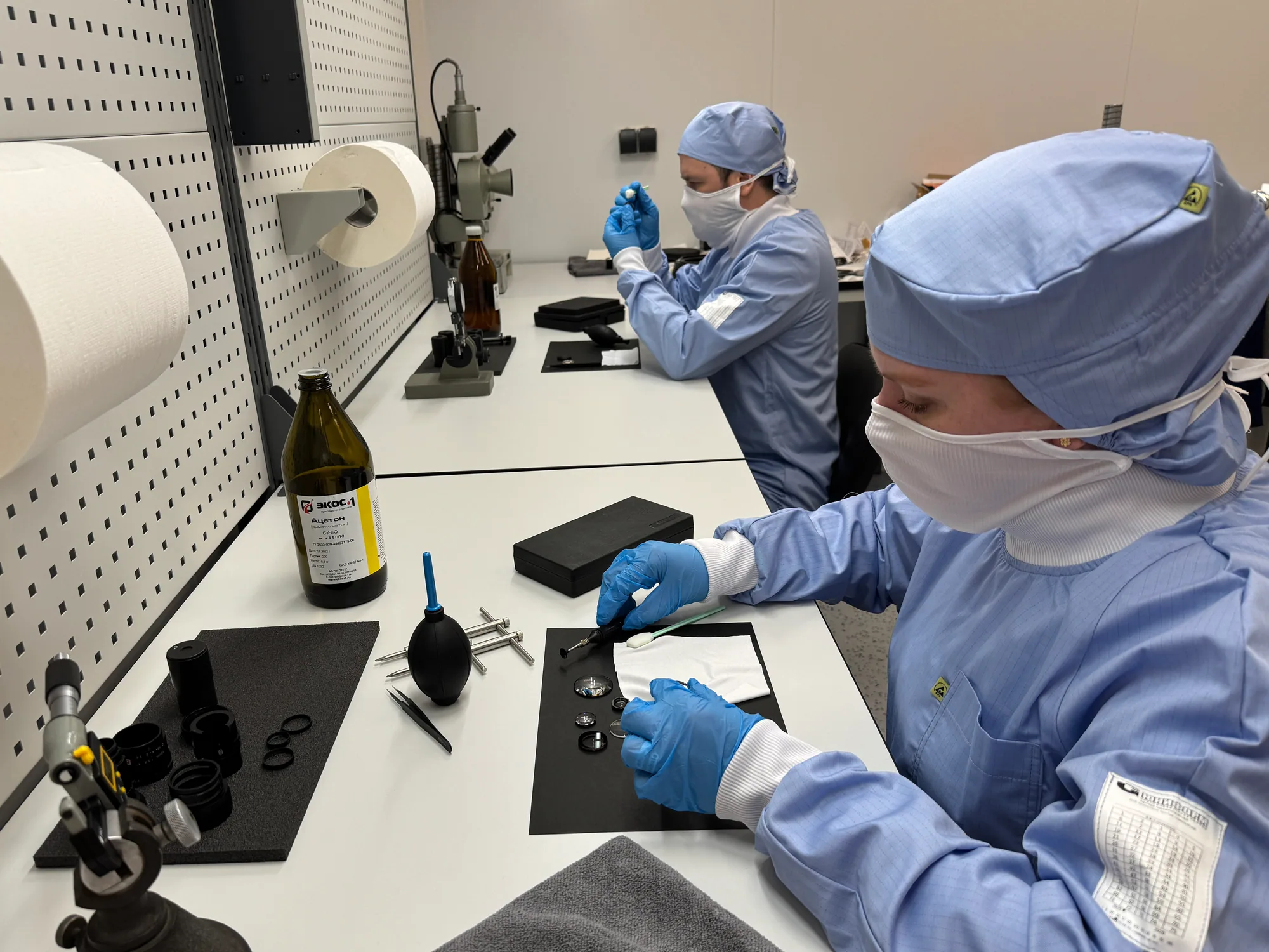 Specialists in protective clothing working with optical components in the cleanroom